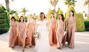 bridesmaids wearing taupe dresses pose for picture with bride after performing bridesmaid duties