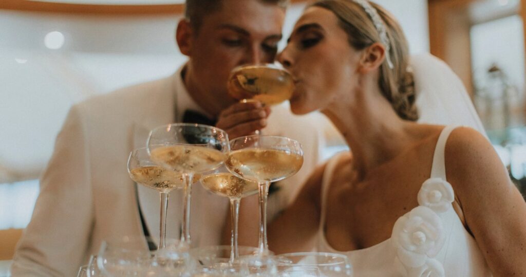portrait of bride and groom sipping champagne at champagne tower 
