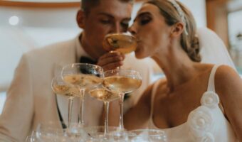 portrait of bride and groom sipping champagne at champagne tower