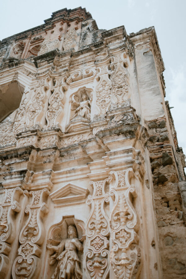 Close-up of an ornate stone church façade with intricate carvings and arches, showing weathered details.