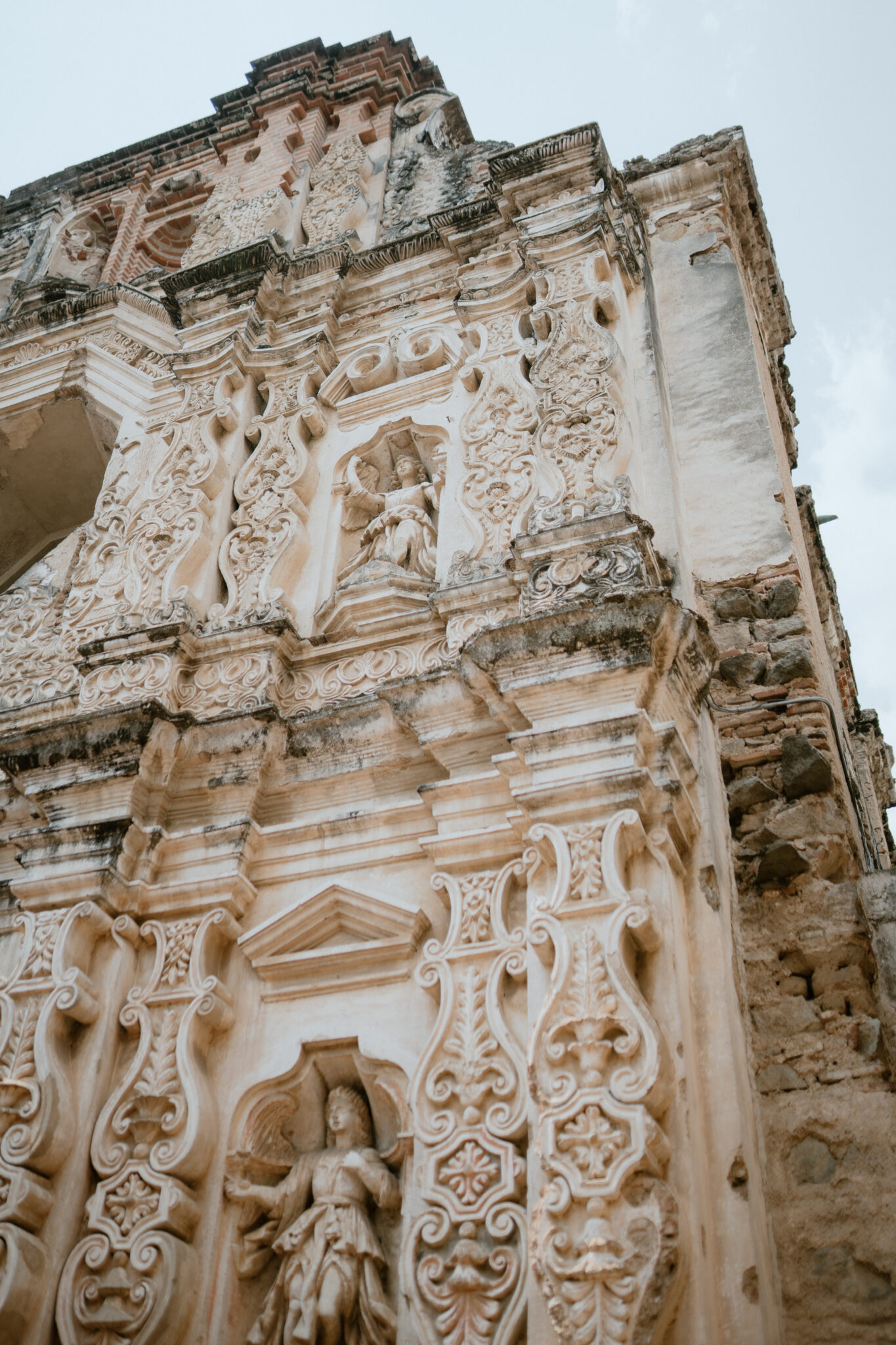 Close-up of an ornate stone church façade with intricate carvings and arches, showing weathered details.
