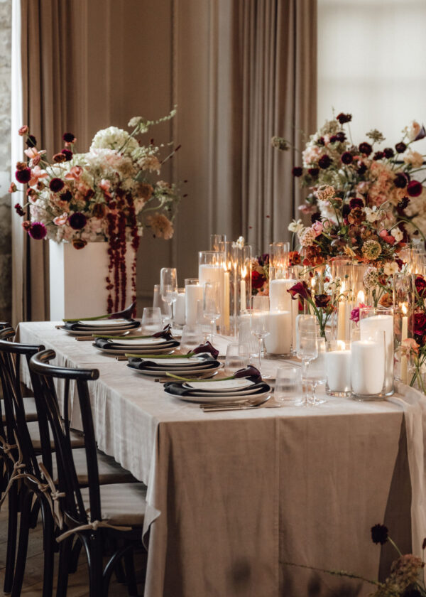 Elegant banquet table with tall floral centerpieces, glassware, and candlelit ambiance at a formal event