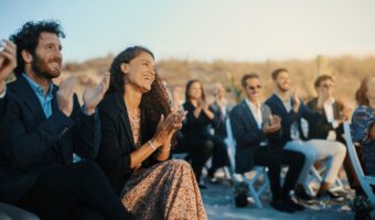 wedding guests sit in awe of bride and groom at outdoor ceremony and immersive destination wedding