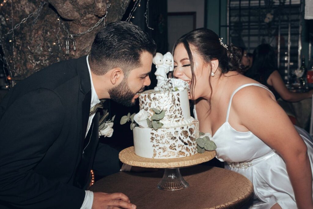 bride and groom biting cake sitting on table